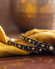 Two decorative bracelets with celestial designs on a yellow fabric background