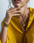 Woman wearing a yellow outfit with jewelry including necklaces and bracelets.