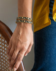 Close-up of a hand wearing gold bracelets with a blurred background