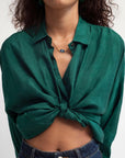 Green button-up shirt tied at the waist worn by a person on a white background