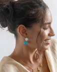 Woman wearing earrings and a necklace with a plain background