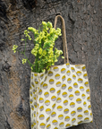 Tote bag with floral design hanging on a tree trunk