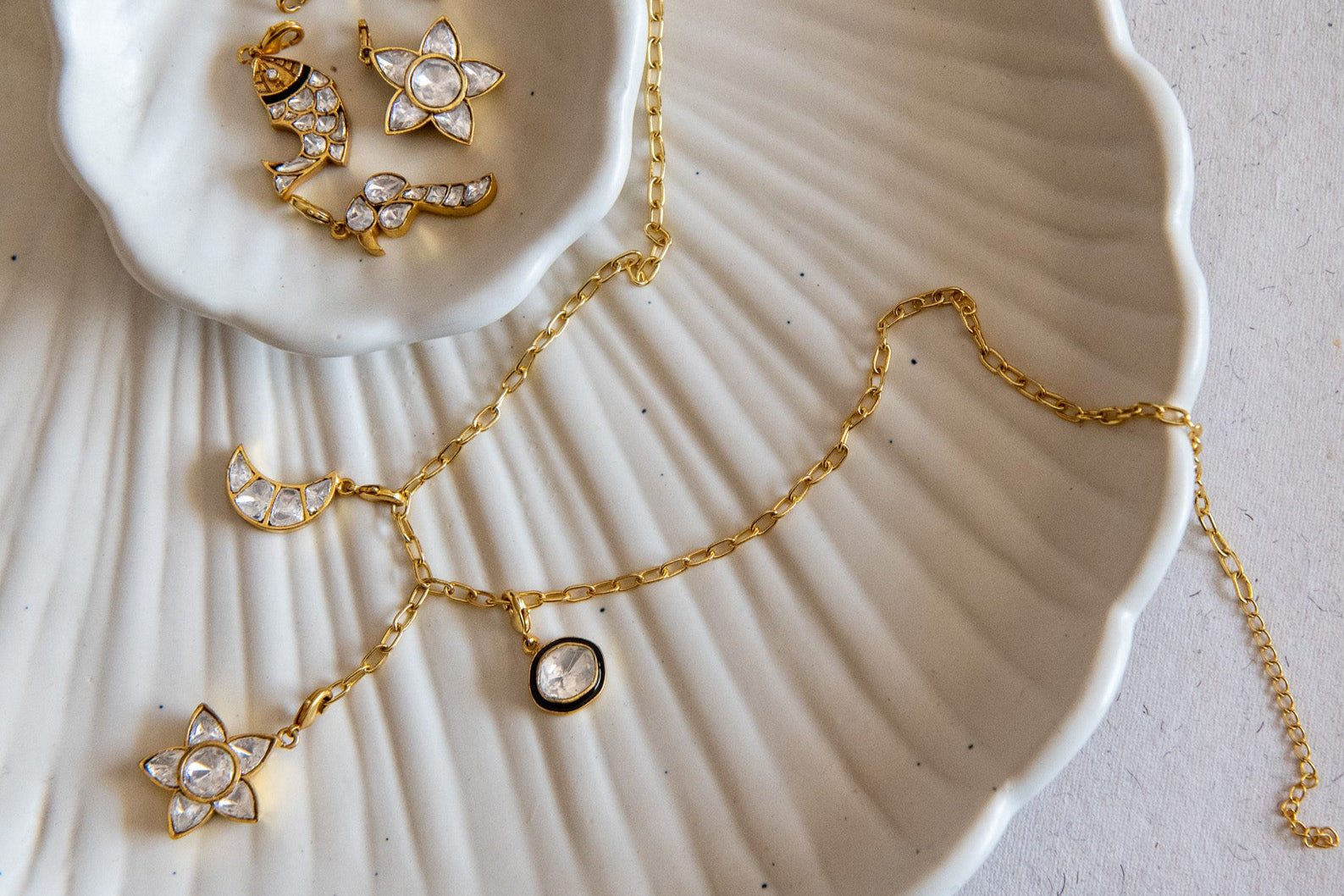 Gold necklace with charms on a white shell