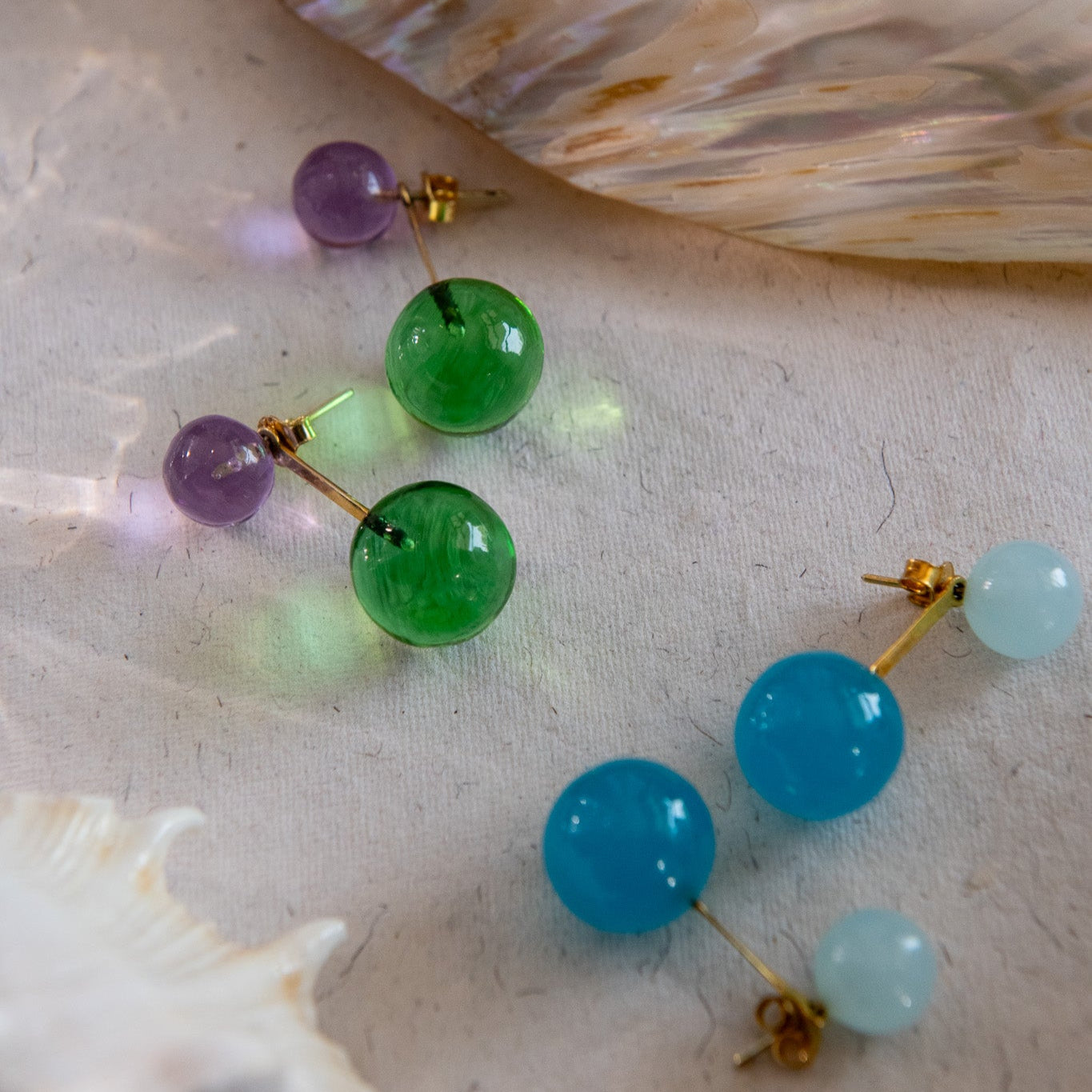 Multicolored bead earrings on a shell background