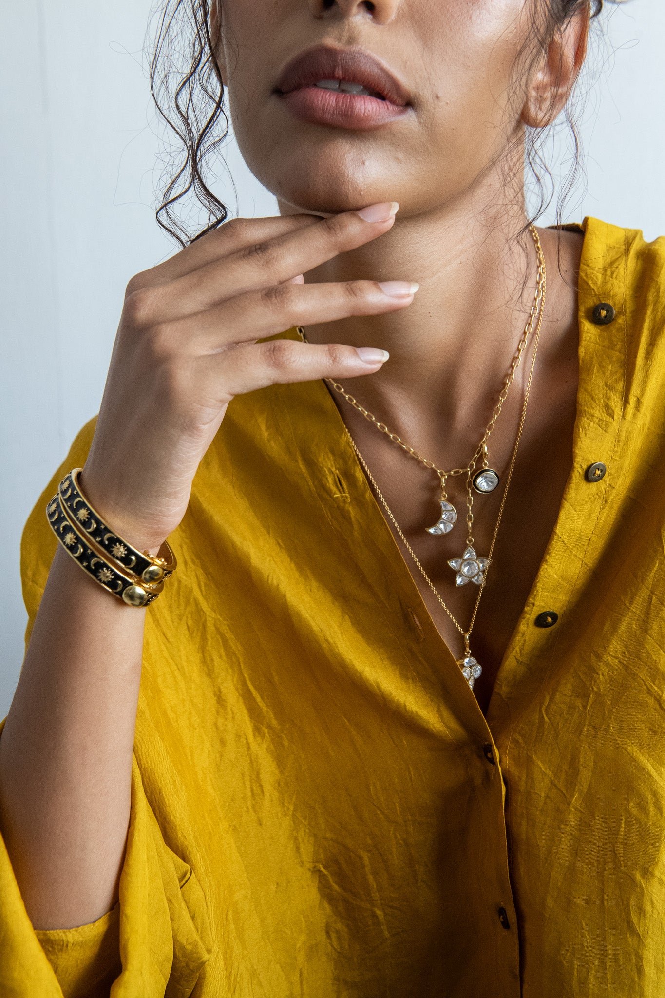 Woman wearing a yellow outfit with jewelry including necklaces and bracelets.