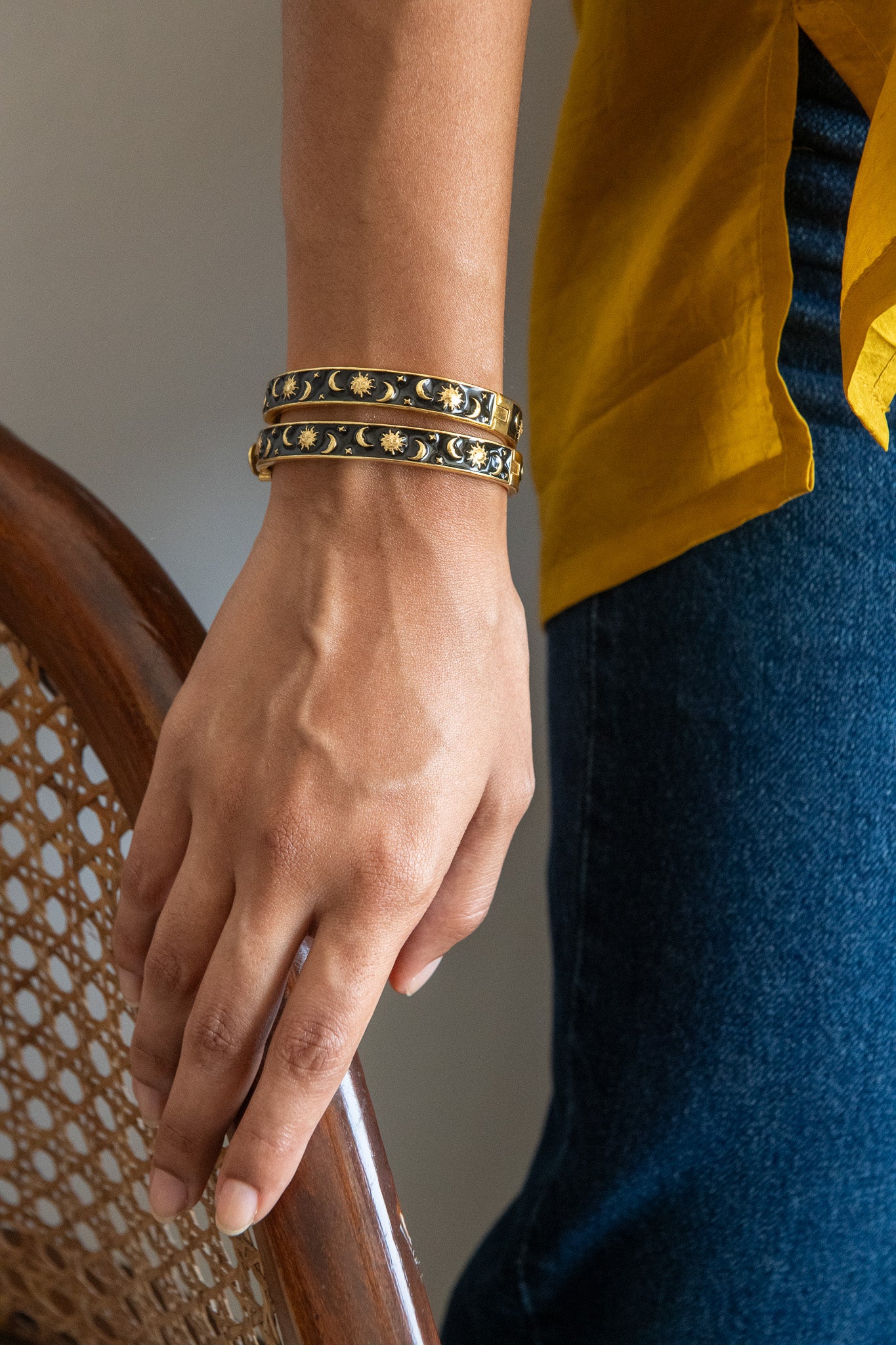 Close-up of a hand wearing gold bracelets with a blurred background