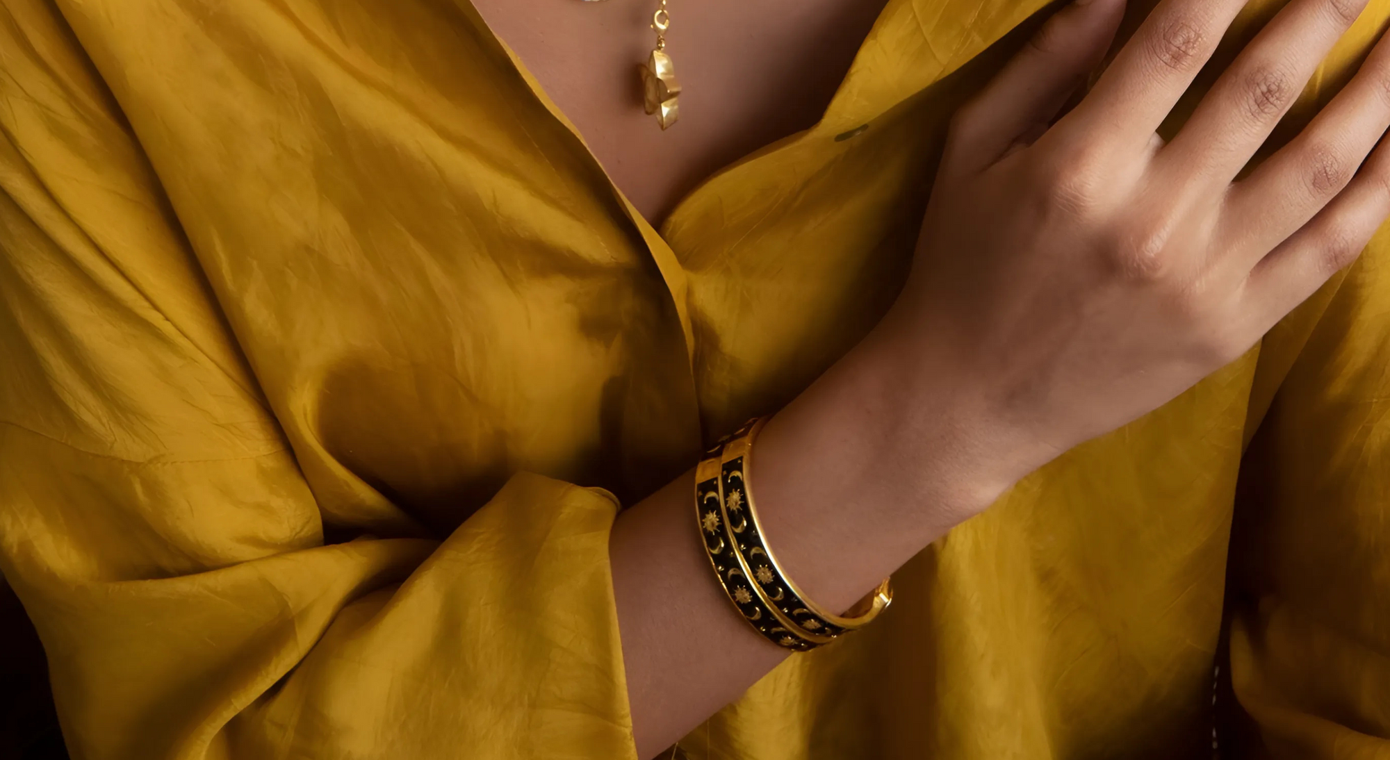 Person wearing a gold bracelet on a yellow garment
