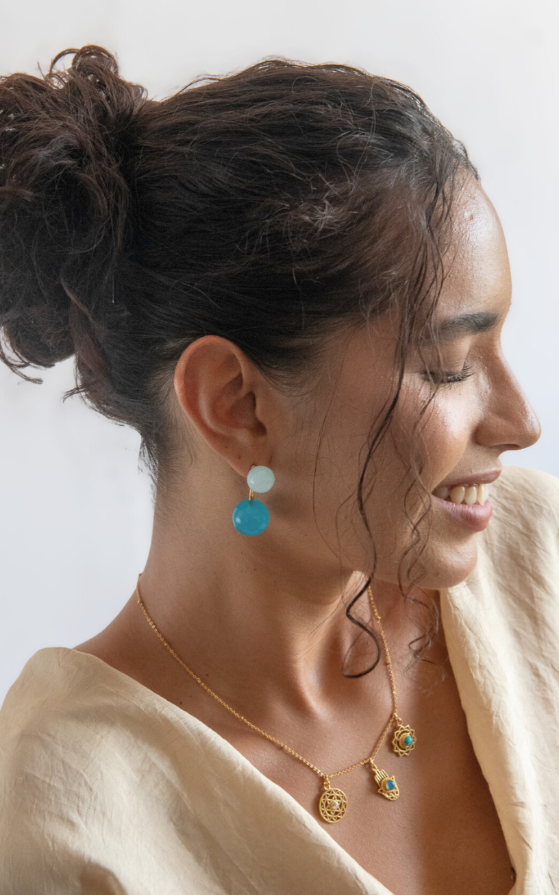 Woman wearing earrings and a necklace with a plain background