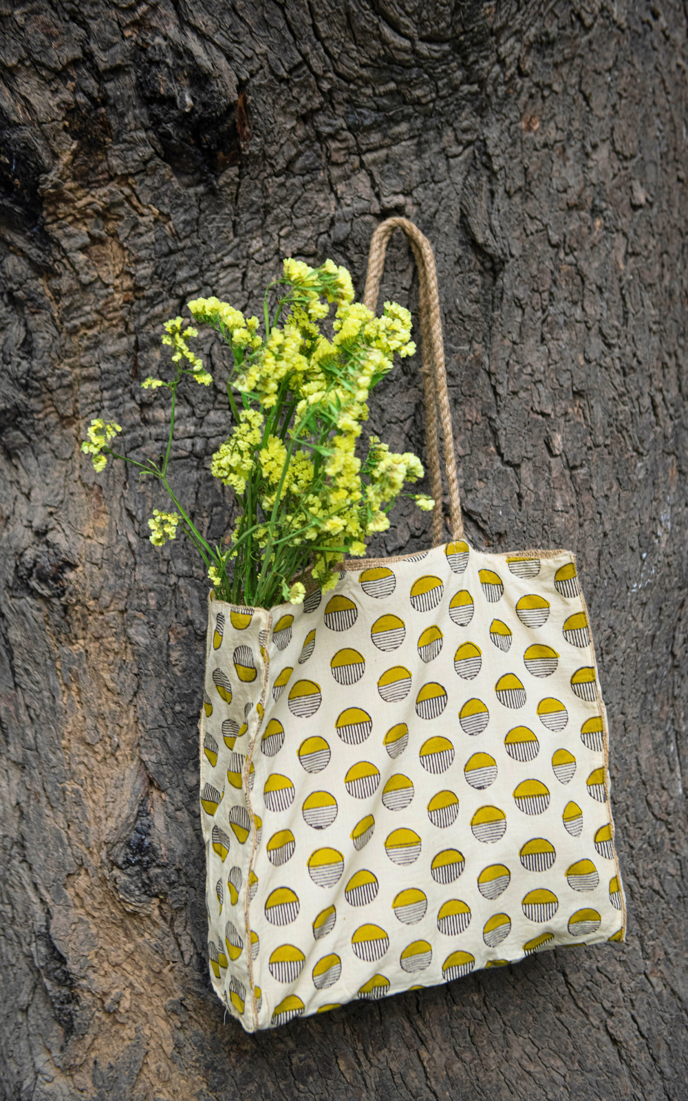 Tote bag with floral design hanging on a tree trunk